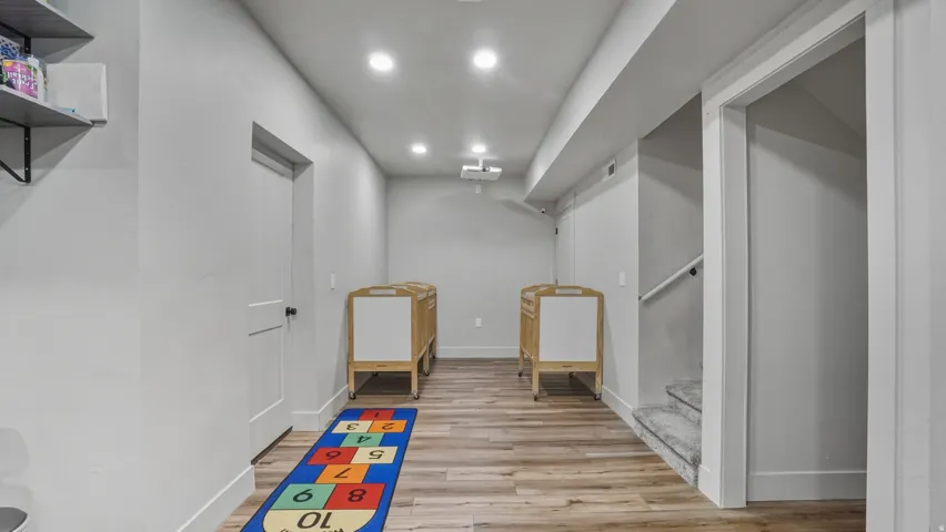 Recessed lighting illuminates wood-finish flooring, complemented by light gray walls