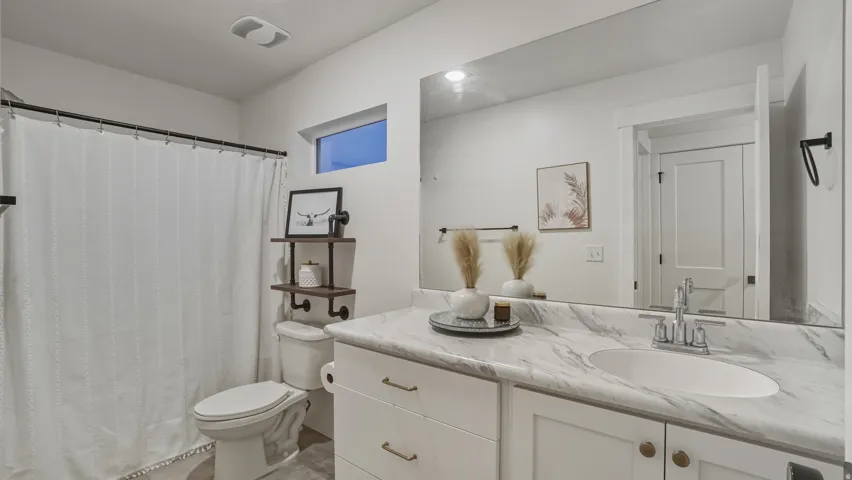 White vanity with an undermount sink, a stone-finish countertop, and brass-tone hardware