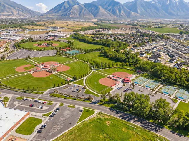Expansive parkland with multiple baseball diamonds, tennis courts, and walking paths