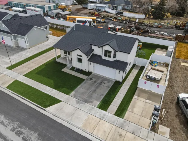 White exterior with black trim, concrete driveway, attached two-car garage, covered porch, and a fenced backyard