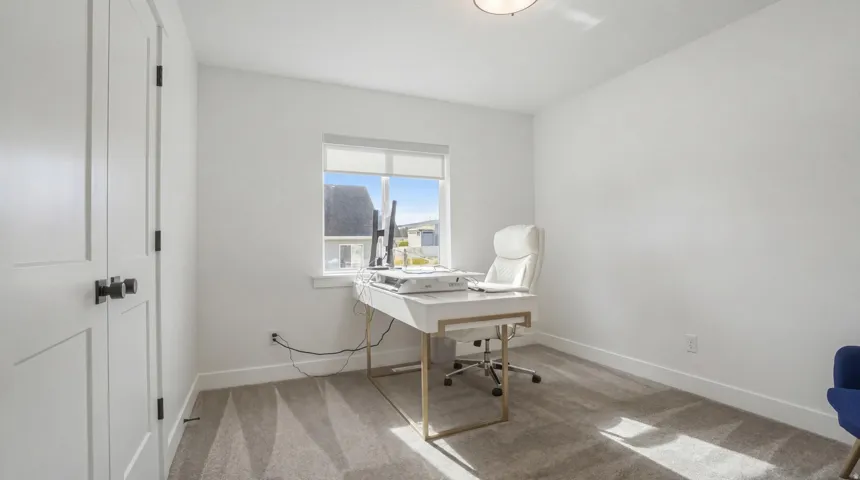 Recessed ceiling lighting, white walls, gray carpeting, and a window with roller shades