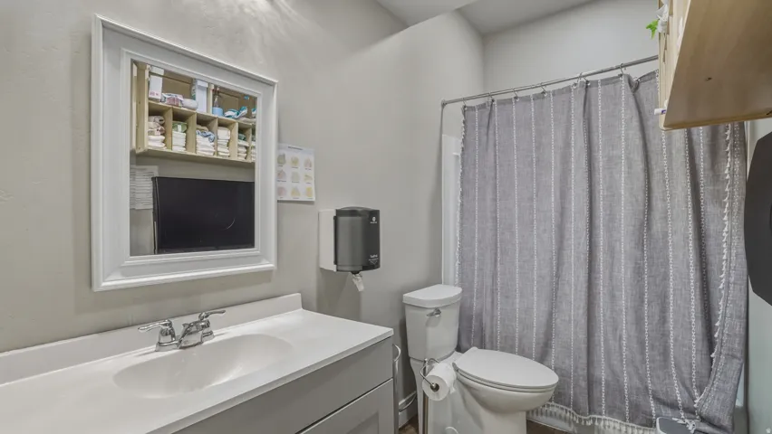 White framed mirror, chrome finish faucet, white countertop, light gray vanity, and a shower with a chrome rod