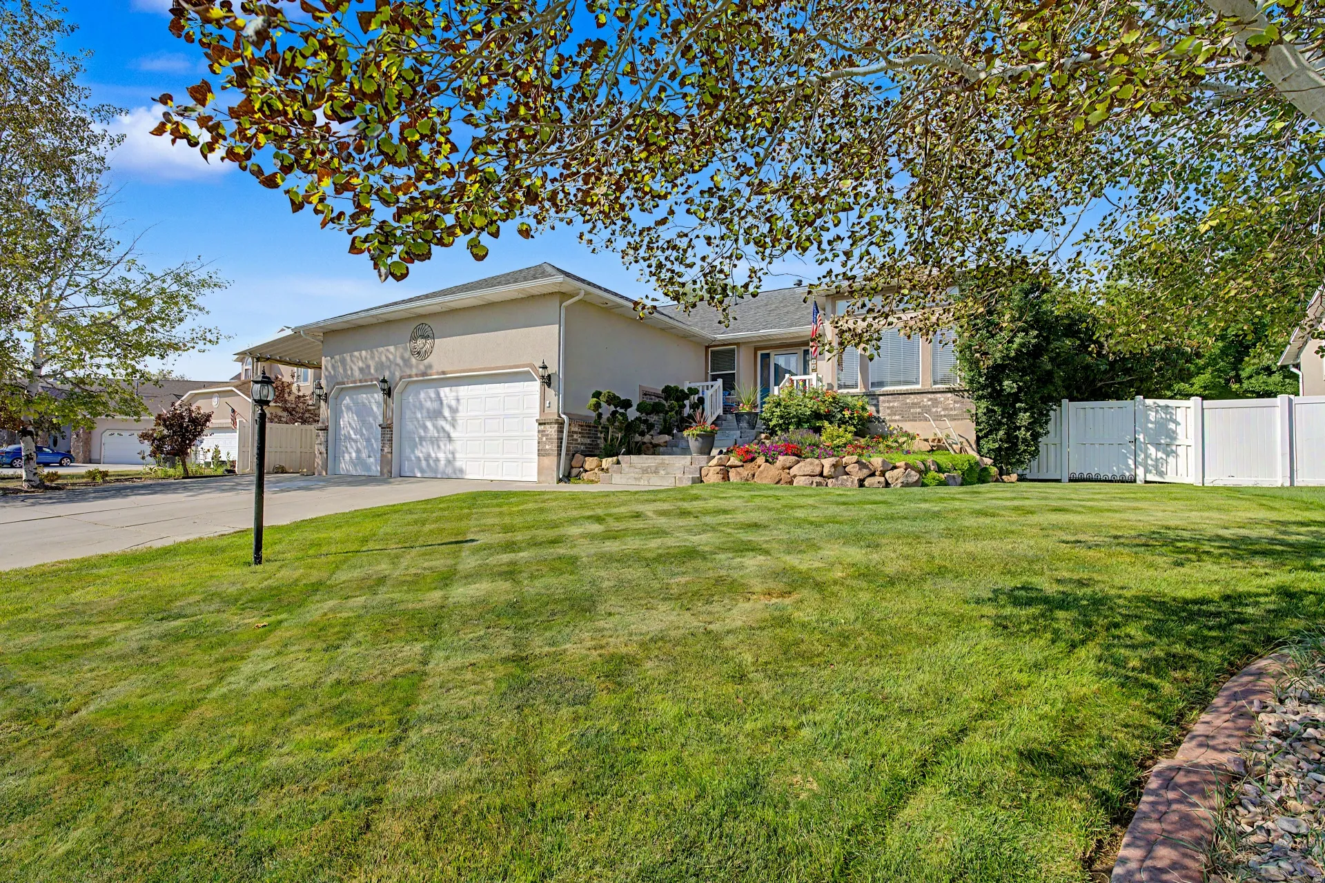 Spacious front-facing lawn with mature tree canopy, brick hardscaping border
