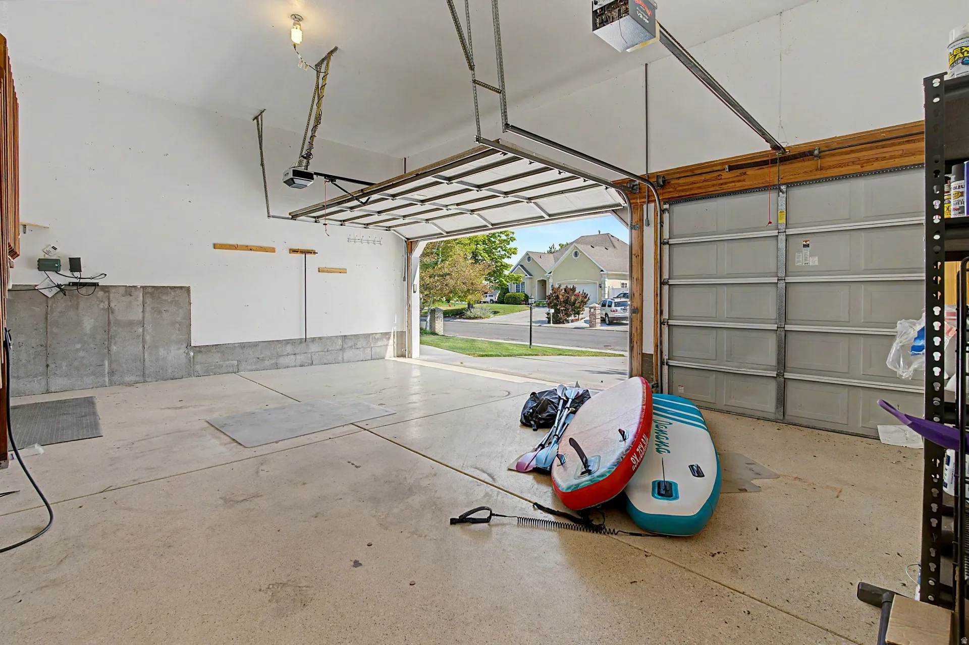 Attached garage with concrete flooring, automatic garage door opener, and a built-in shelving unit