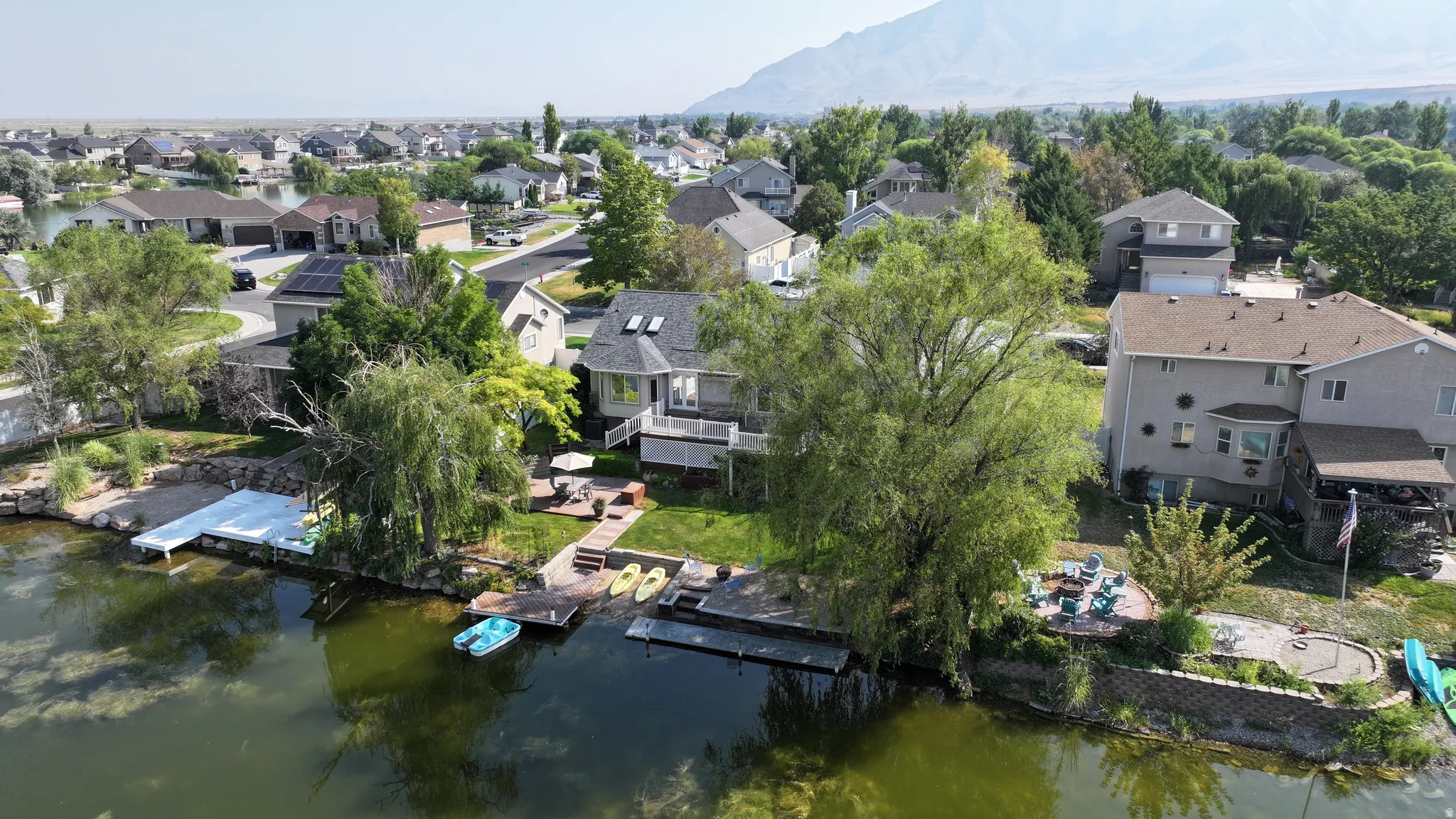 Waterfront property featuring multiple docks, a terraced retaining wall, and a raised deck