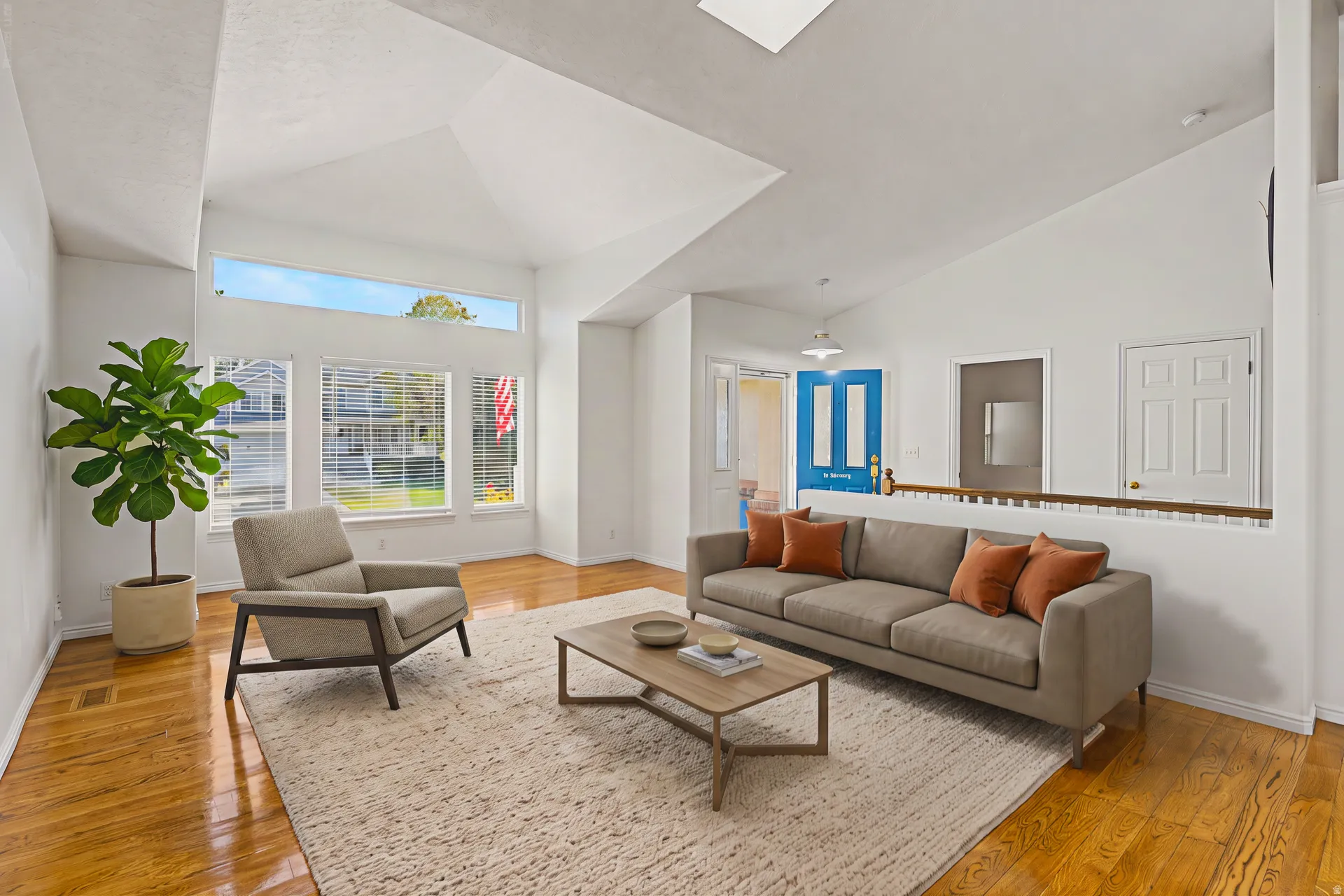 Virtually Staged Living Room, Vaulted ceilings, skylight, wood-finish flooring, multiple windows, and a built-in half wall with wood railing