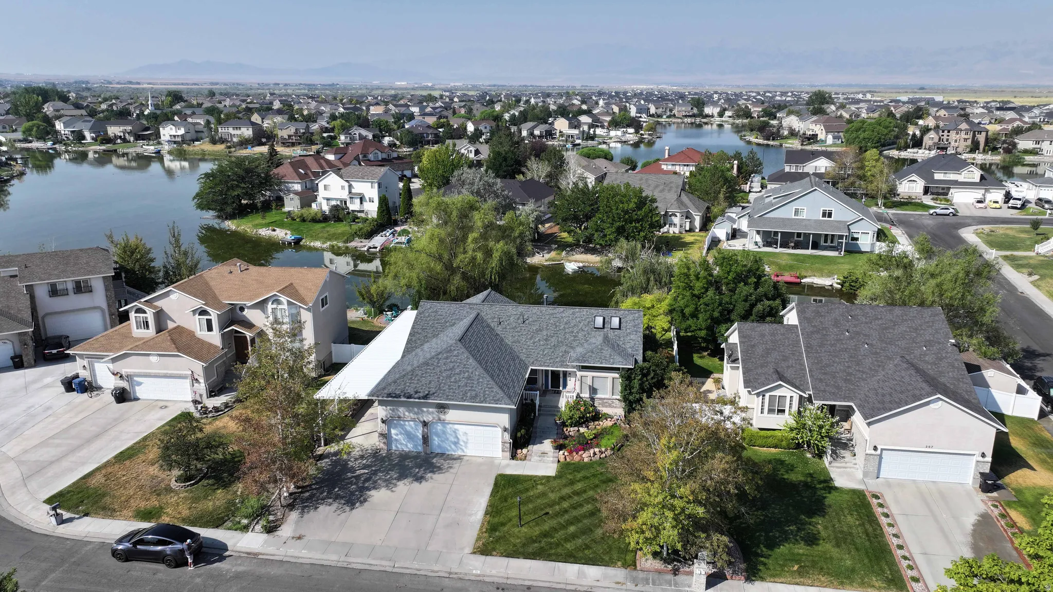 Lakeside property featuring a multi-level structure, attached garage, and a landscaped front yard