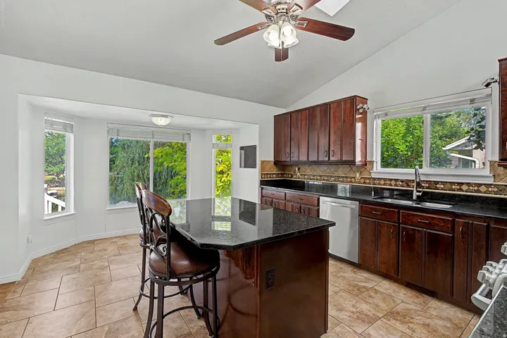 Kitchen featuring dark wood cabinetry, a central island with a dark countertop, stainless steel appliances, and tile flooring
