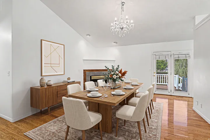 Virtually Staged dining space with Vaulted ceilings, wood-finish flooring, recessed lighting, double French doors, and an elegant chandelier