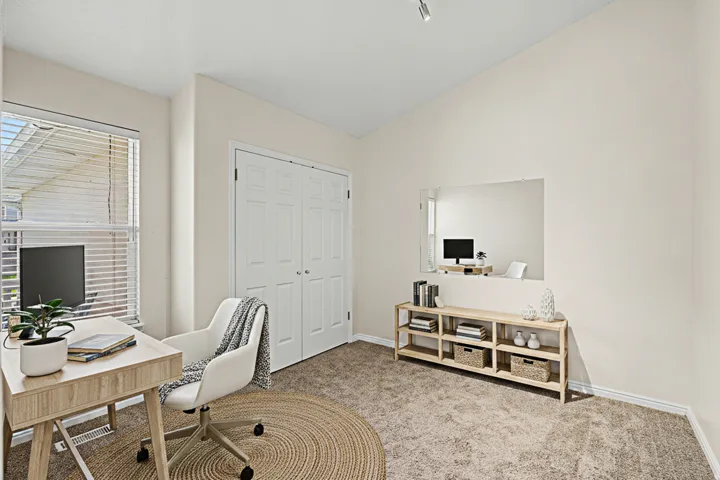Virtually Staged office/flex space with closet, could serve as a bedroom with Vaulted ceiling, neutral wall paint, window with blinds, carpet flooring, and double bi-fold closet doors