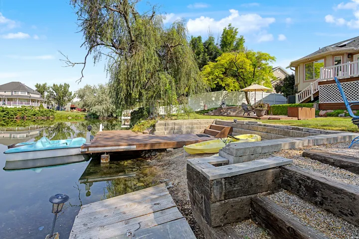 Waterside property featuring a private boat dock, multi-tiered landscaping, and a built-in outdoor seating area