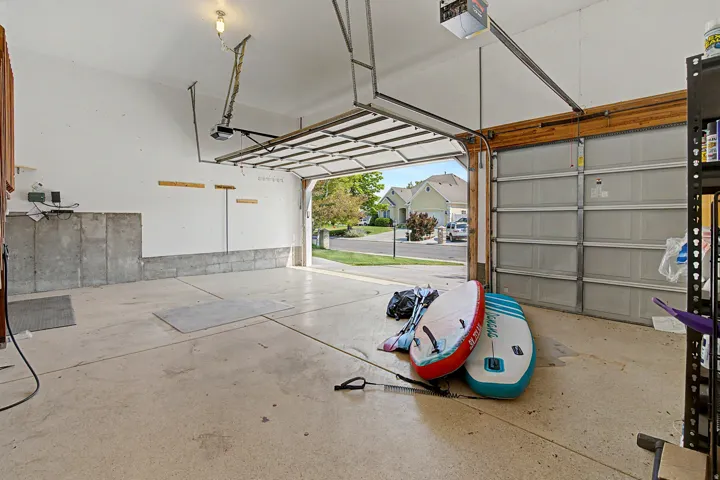 Attached garage with concrete flooring, automatic garage door opener, and a built-in shelving unit