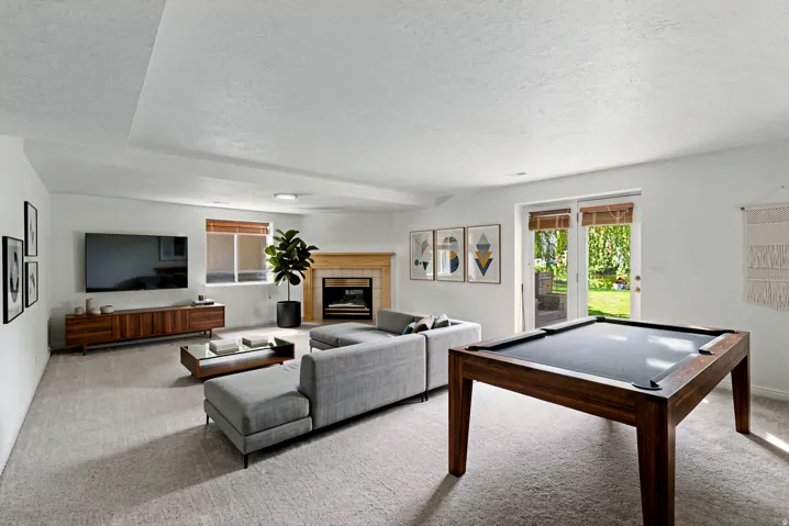 Virtually Staged, spacious living area featuring a fireplace with a wood mantel, glass-paneled patio doors, and recessed lighting