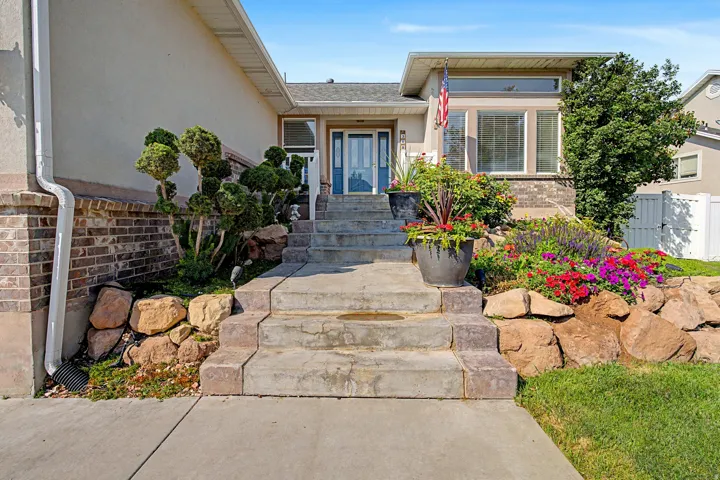 Beautifully landscaped home with tiered landscaping featuring natural rock elements and vibrant floral plantings