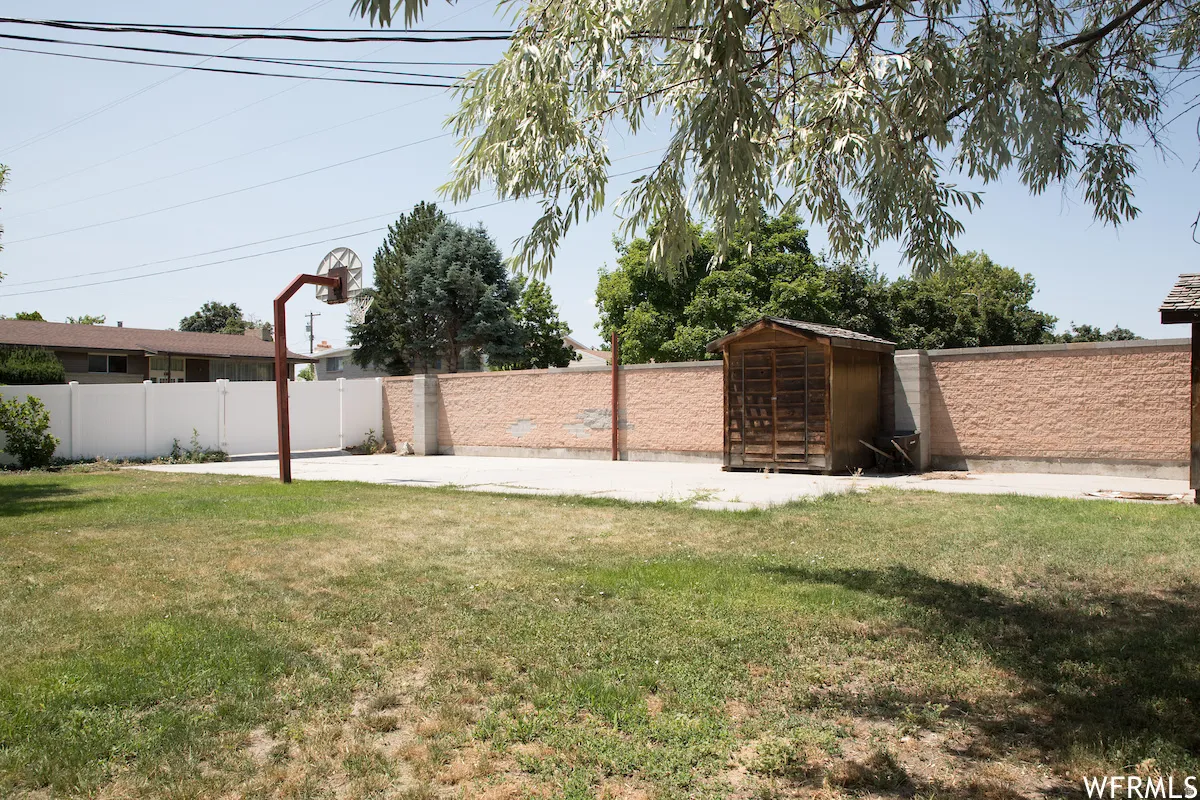 Expansive backyard featuring a concrete pad, a freestanding basketball hoop, and a wood-sided storage shed