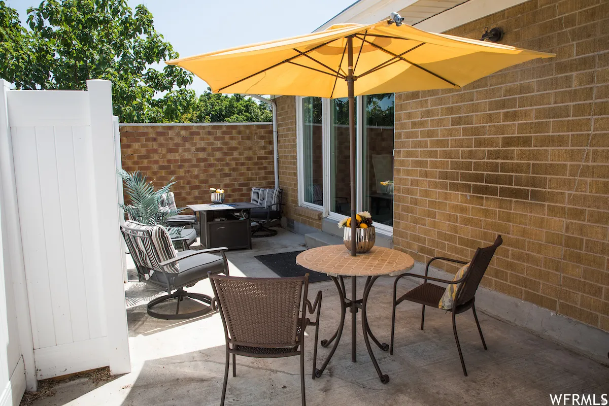 Paved patio area featuring brick wall construction and a white privacy fence