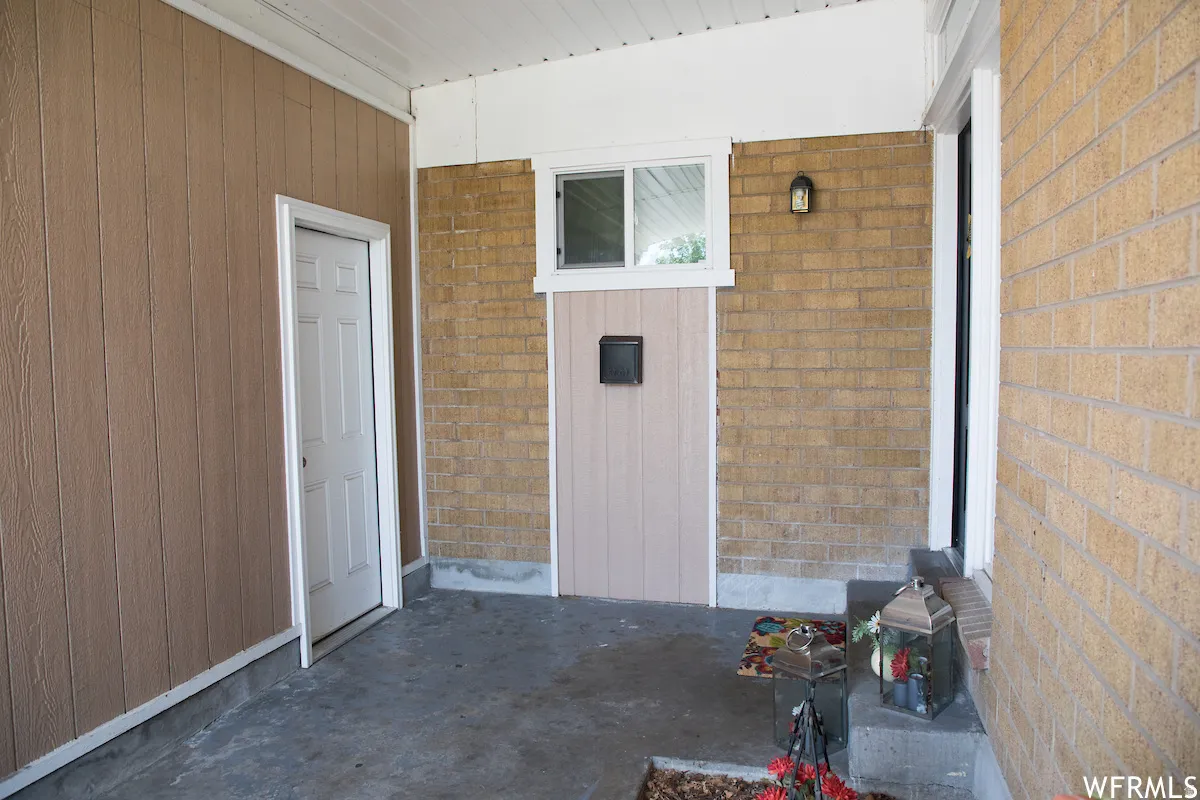 Covered porch featuring brick and vertical panel siding