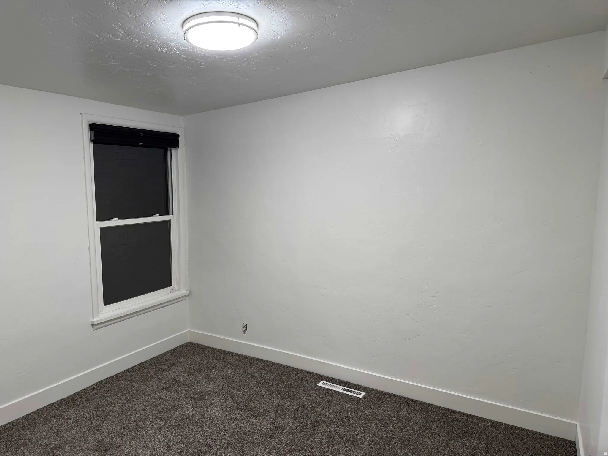 Recessed window with dark roller shades, white trim, and neutral-toned wall paint