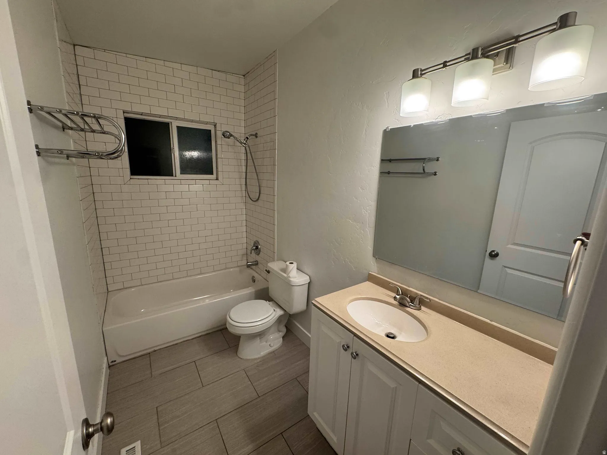 Bathroom featuring a vanity with a light-toned countertop, a rectangular mirror, and a three-light fixture