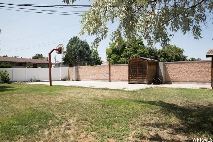 Expansive backyard featuring a concrete pad, a freestanding basketball hoop, and a wood-sided storage shed