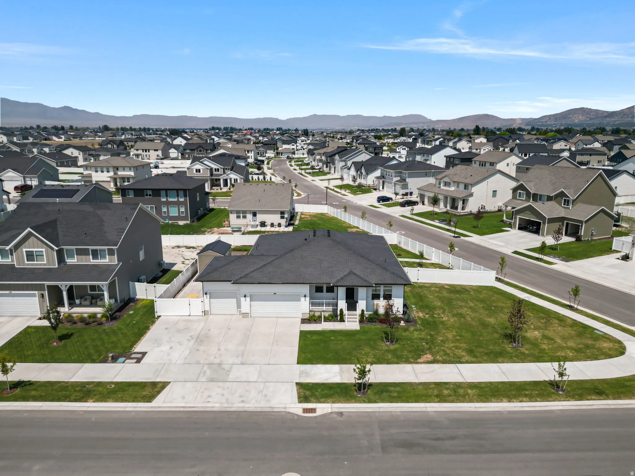 Single-story residence with a three-car garage, concrete driveway, and a white privacy fence
