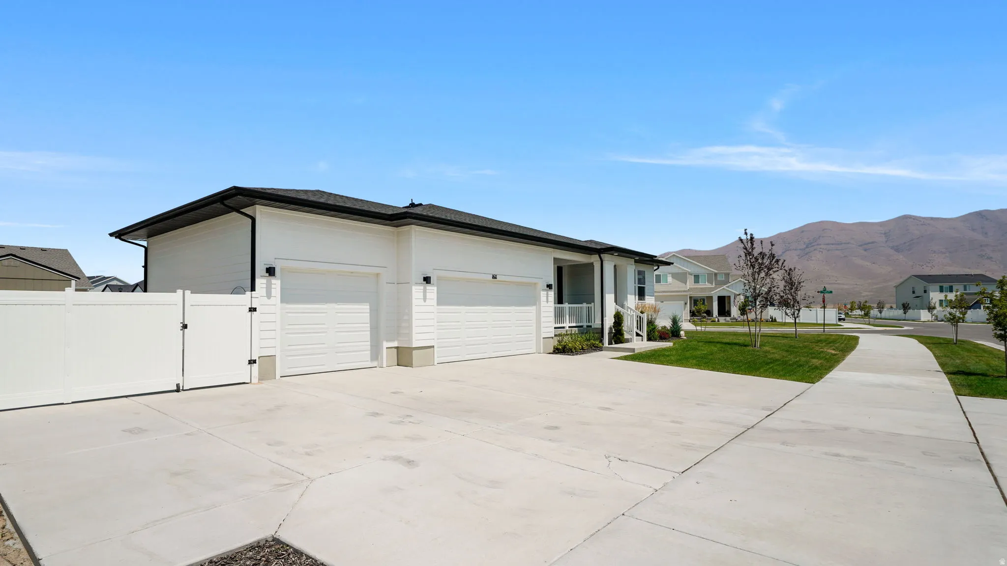 Paved driveway with ample space, two single-car garages, and a white privacy fence