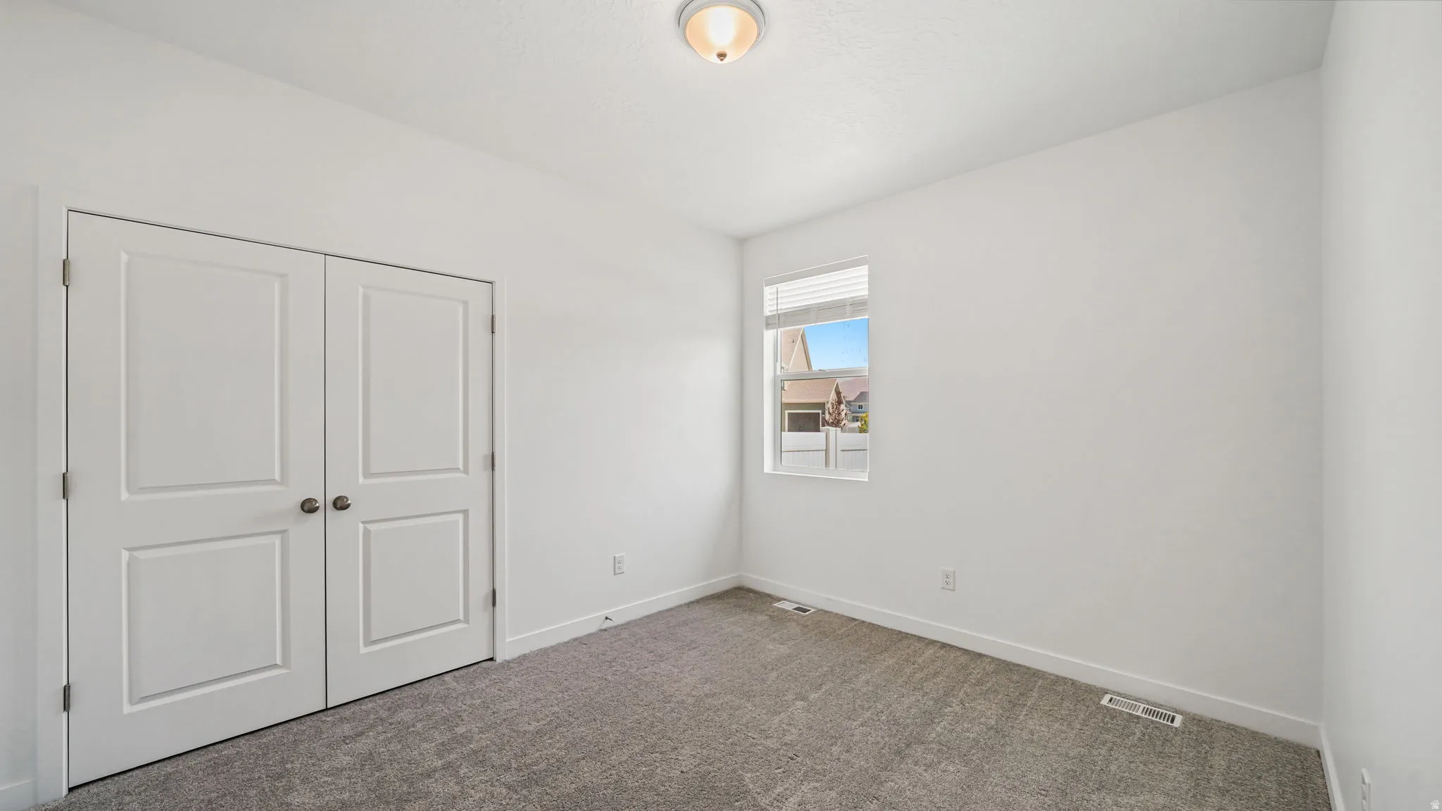 Neutral-toned carpeting, white walls, and a ceiling-mounted light fixture