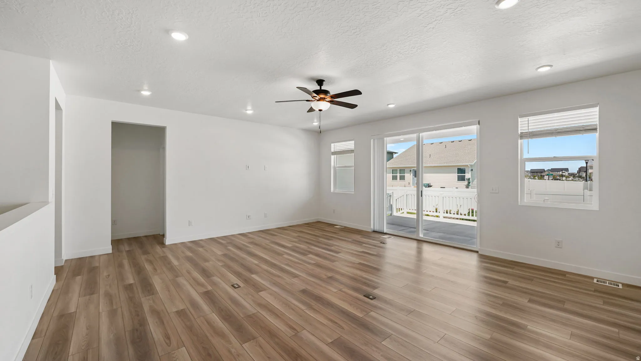 Recessed lighting, wood-finish flooring, ceiling fan, sliding glass door, and multiple windows
