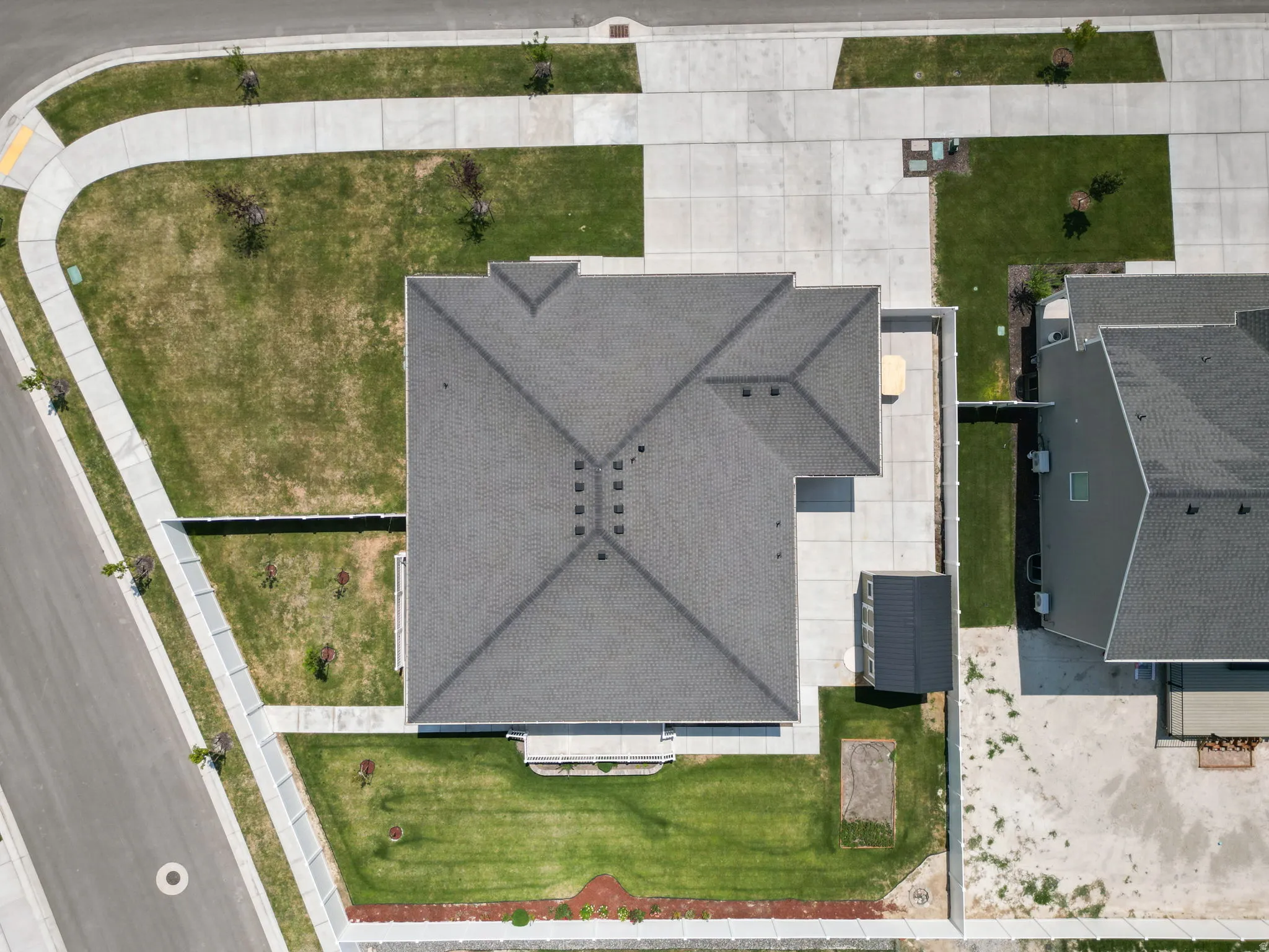 Gabled roofline with dark shingles, concrete driveway, concrete walkways, and a fenced perimeter