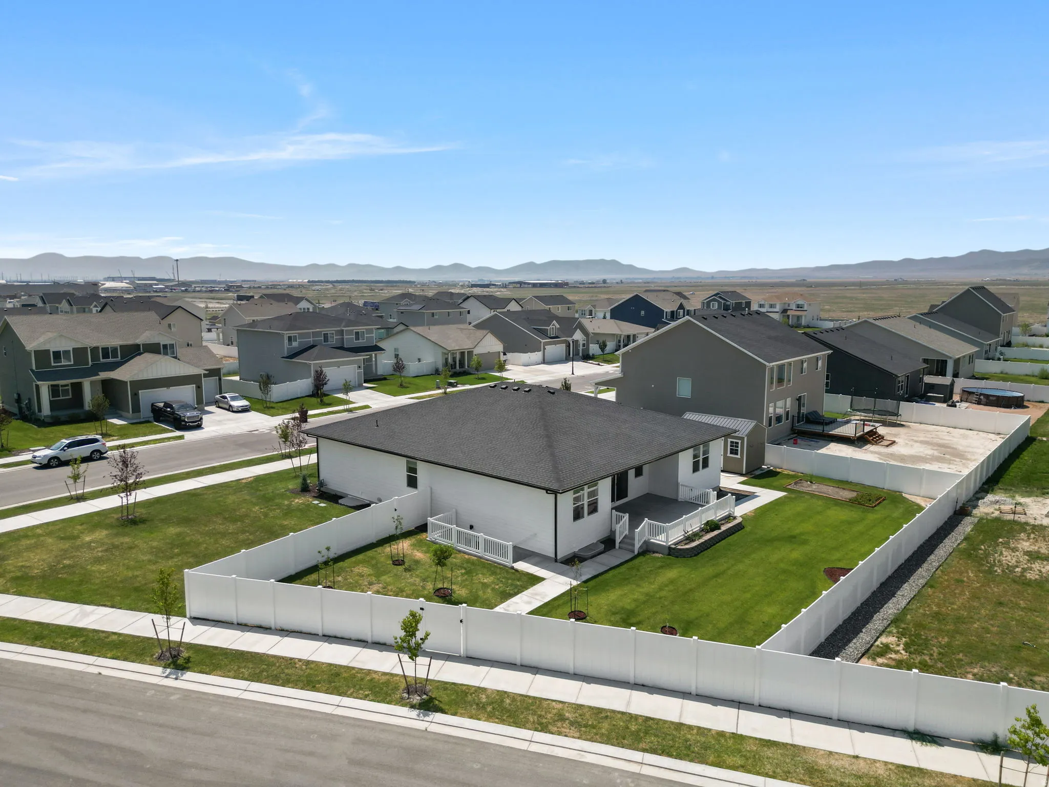 Rear deck with white railing, expansive green lawn, and white privacy fencing