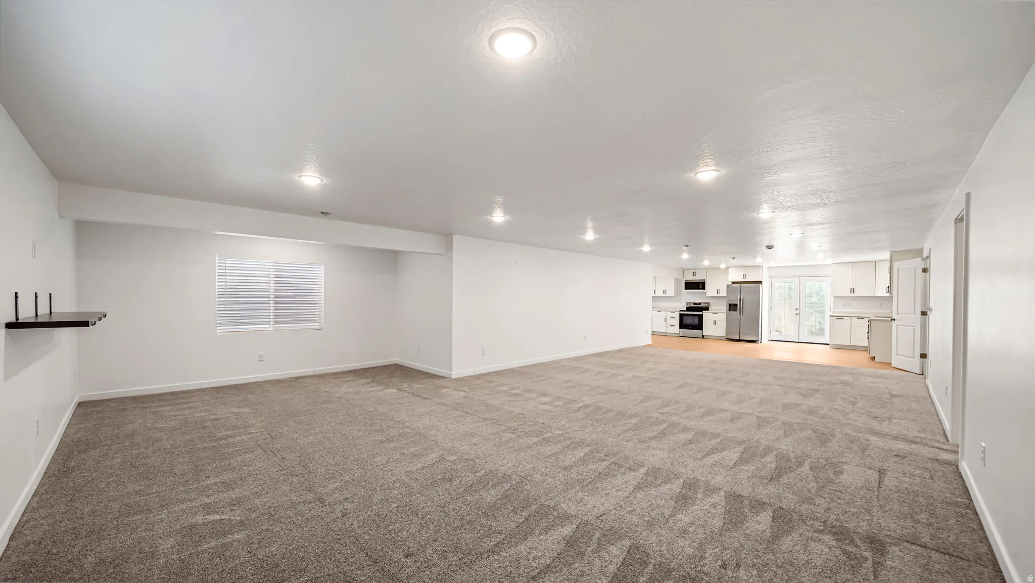 Expansive open-concept living area featuring recessed lighting, a window with horizontal blinds, and carpet flooring