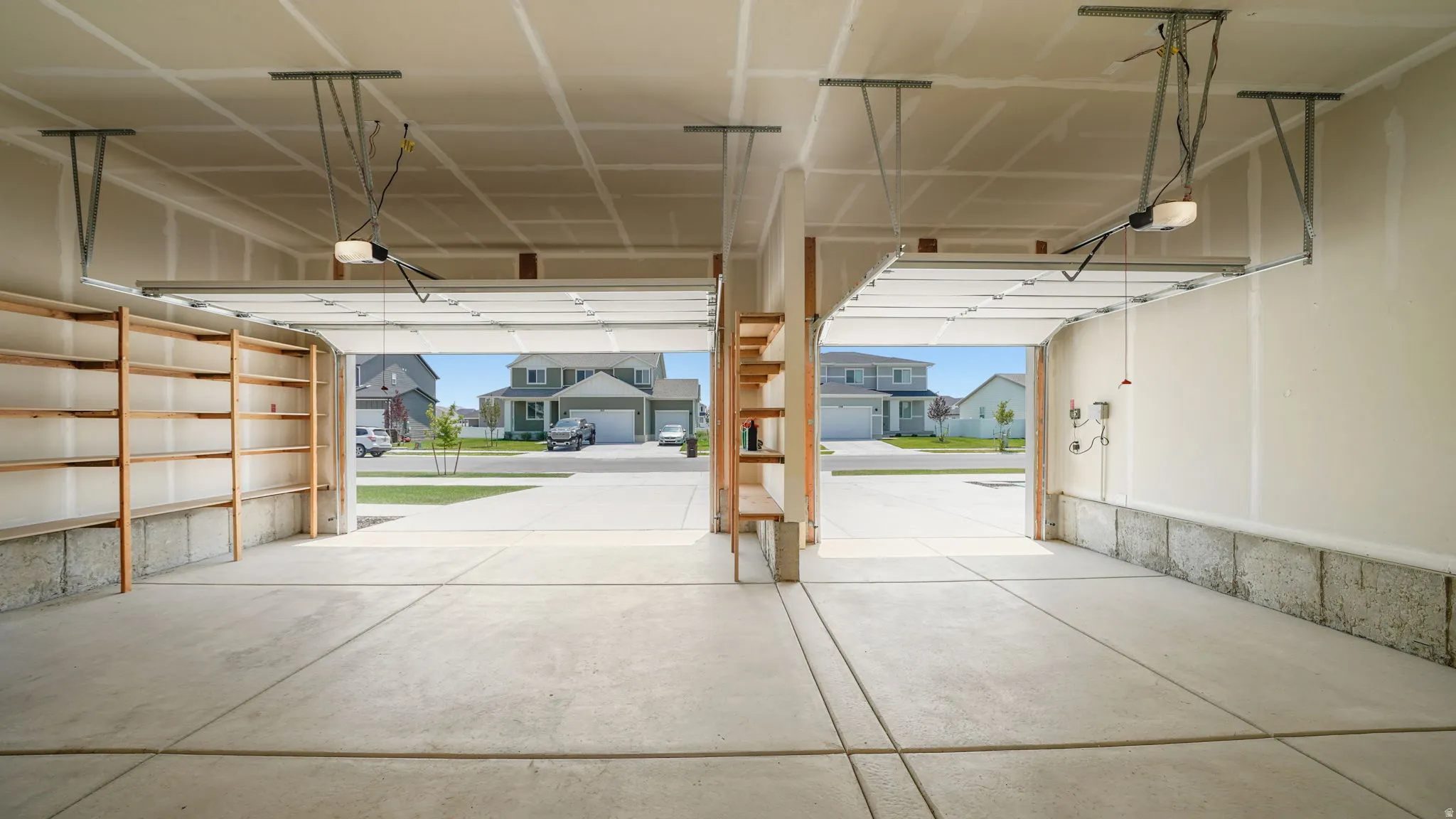 Three-car garage featuring concrete flooring, built-in shelving, and automatic garage door openers