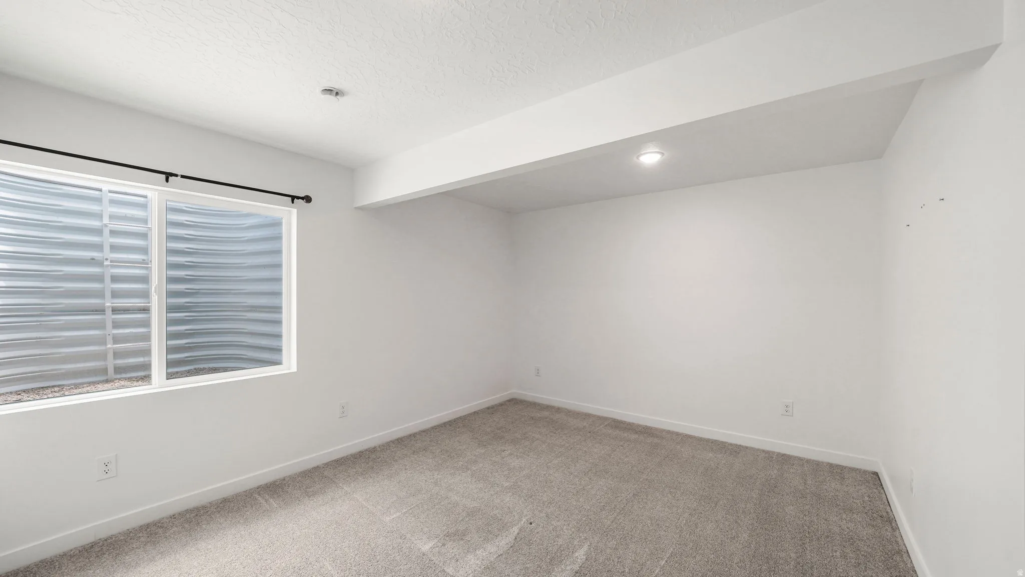 White walls, recessed lighting, and a neutral carpeted floor
