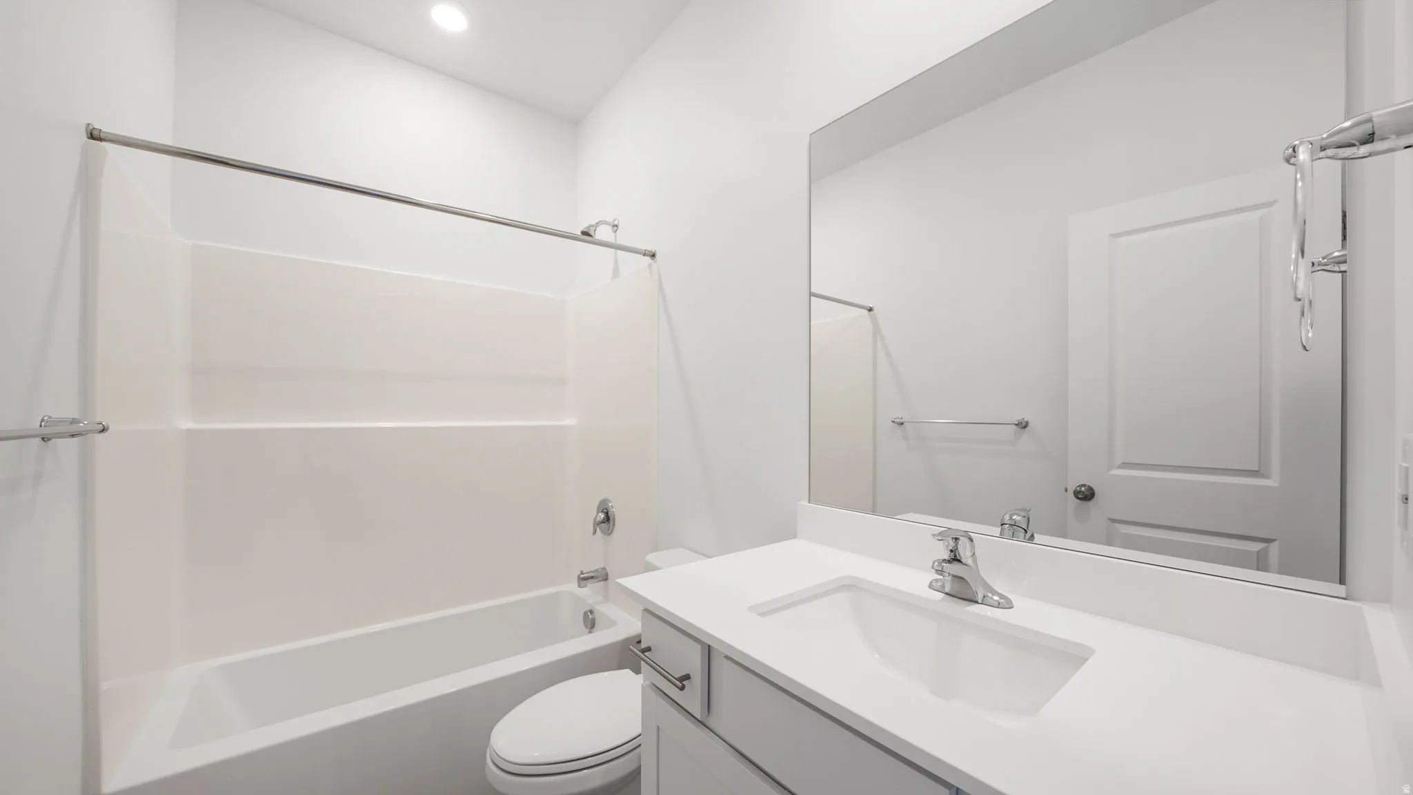 Full bathroom featuring a white tub/shower combination, a single vanity with an integrated sink, a large wall-mounted mirror, and recessed lighting