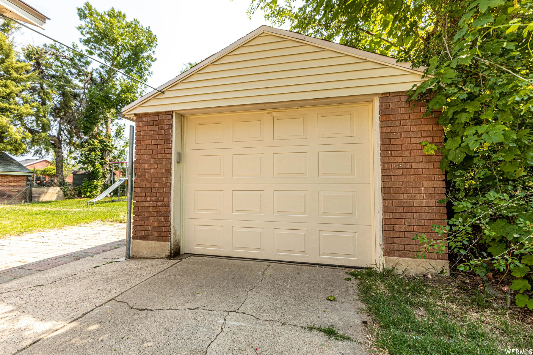 Detached garage featuring brick and siding exterior, a pitched roof, and a panel garage door