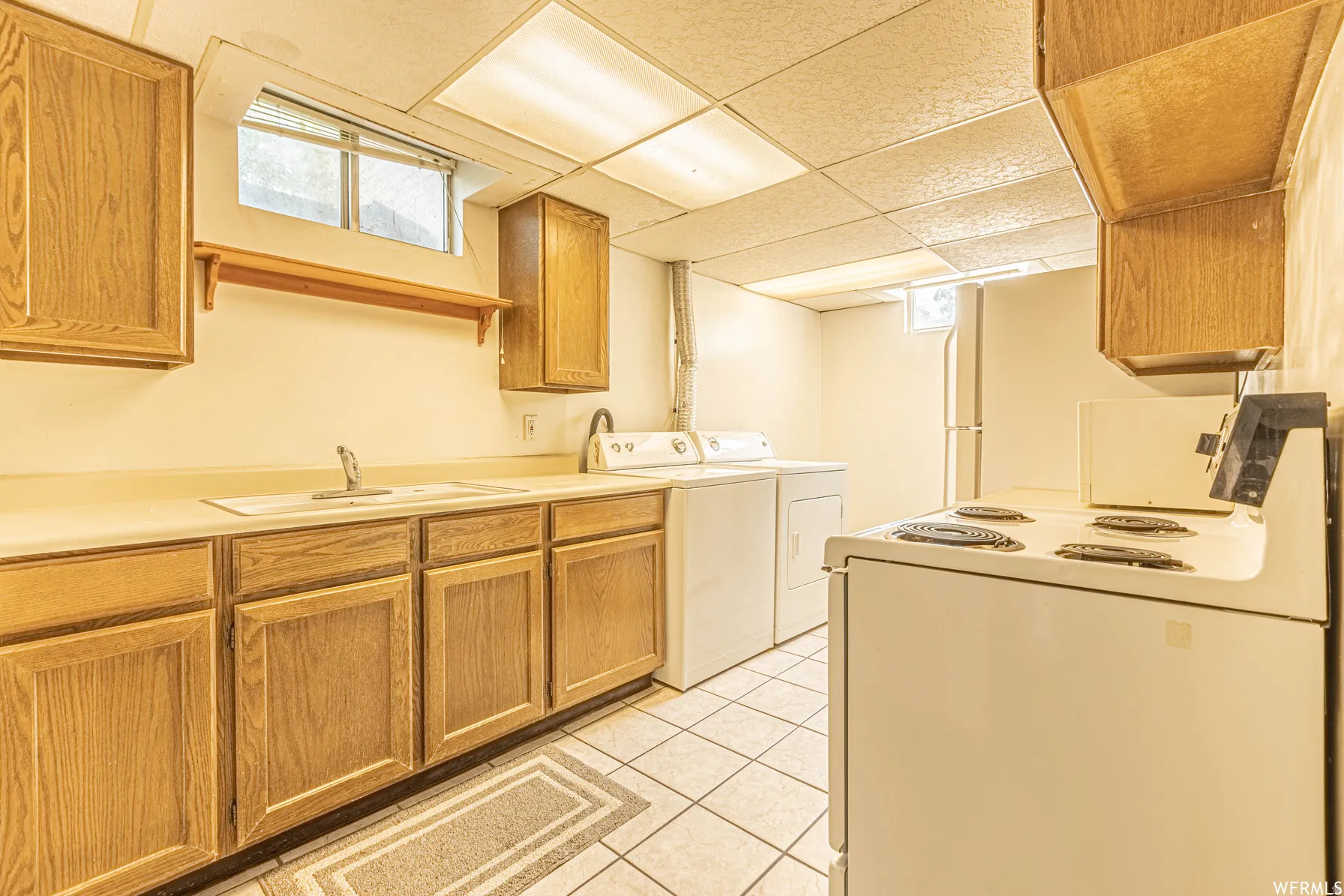 Kitchenette featuring wood-finish cabinetry, a single basin sink, and tile flooring