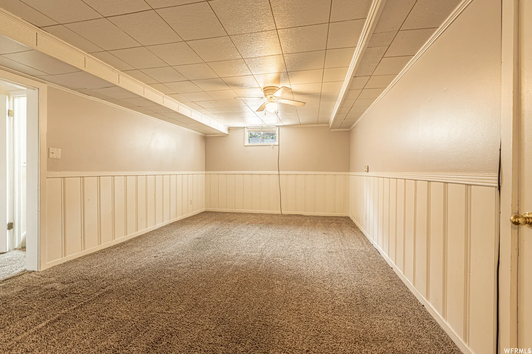 Expansive room featuring carpet flooring, wainscoting, and a drop ceiling with integrated lighting