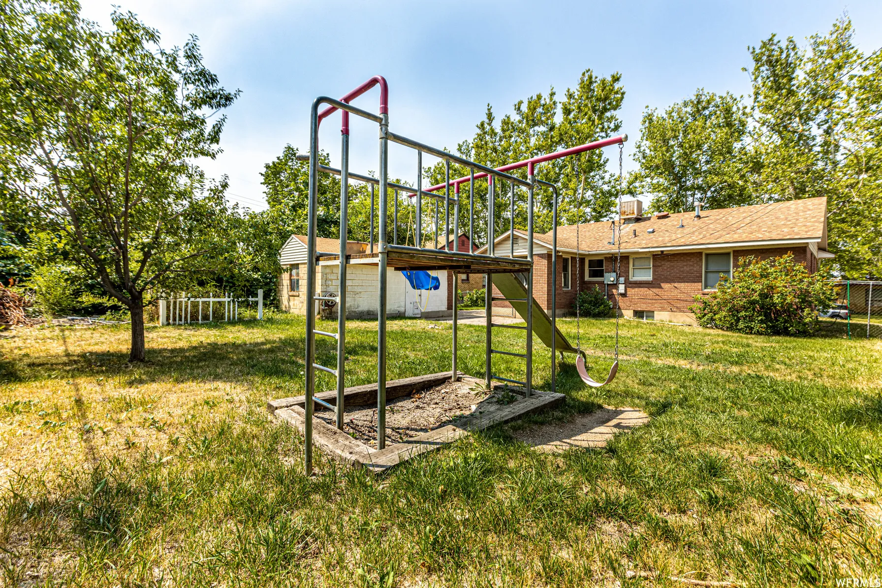 Expansive backyard featuring a brick exterior structure and mature trees