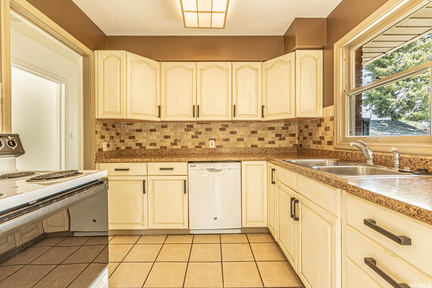 Kitchen featuring tile flooring, white cabinetry with dark hardware, a mosaic tile backsplash, and a double basin sink