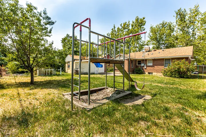 Expansive backyard featuring a brick exterior structure and mature trees