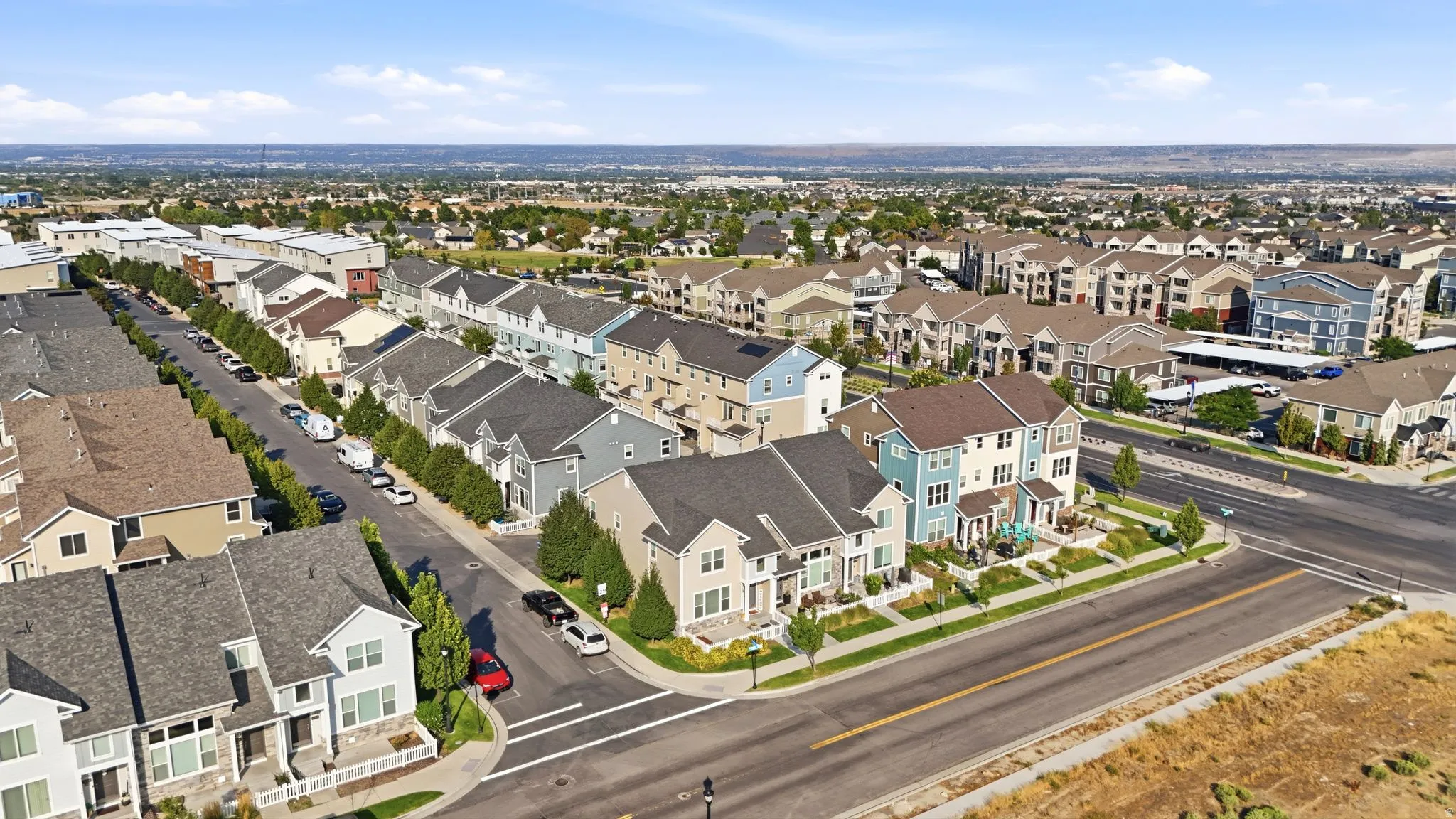 Community setting featuring a variety of multi-story residences, tree-lined streets, and paved roadways