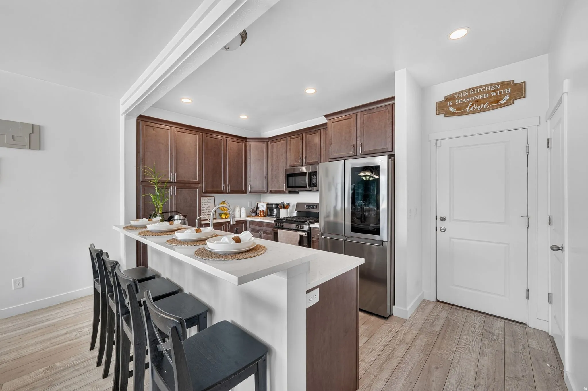 Kitchen with white countertops, wood-finish flooring, dark wood cabinetry, and stainless steel appliances