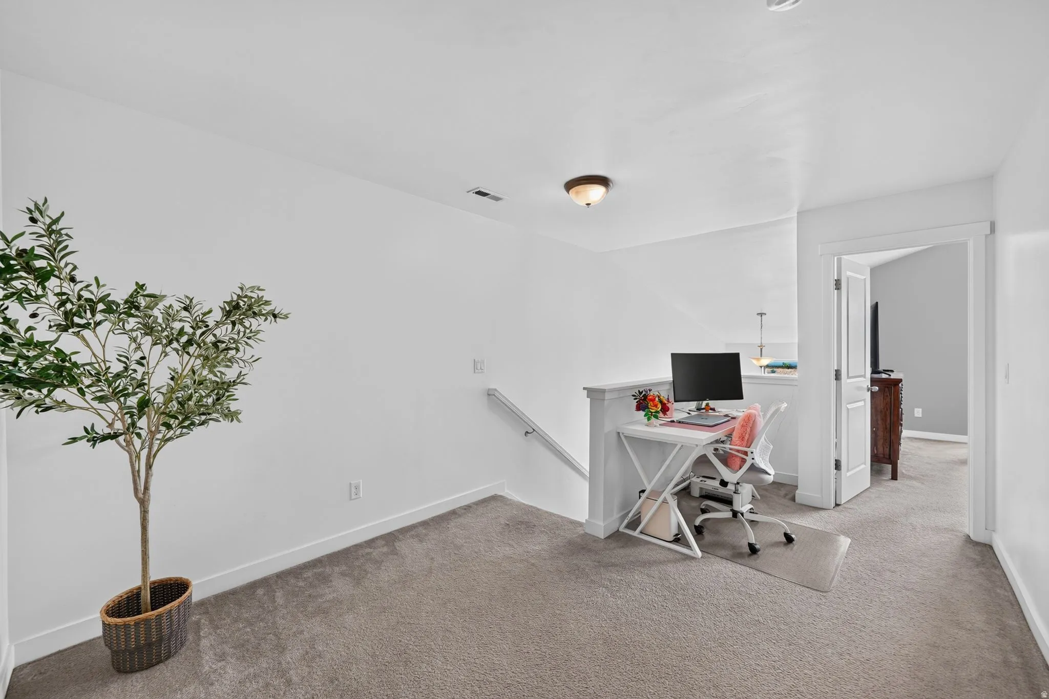 Carpeted loft area with white painted walls, a built-in railing, and a flush-mount ceiling light fixture