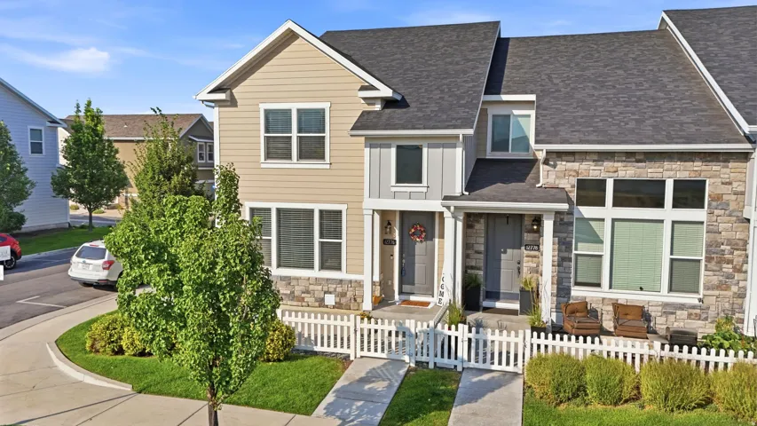 Modern townhome exterior with mixed material facade, white picket fence, and dual paved driveways