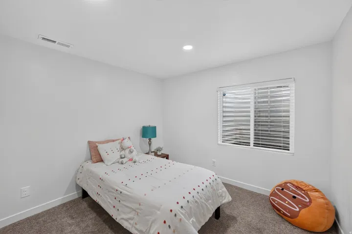 Textured carpet flooring, white walls, recessed lighting, and a window with blinds