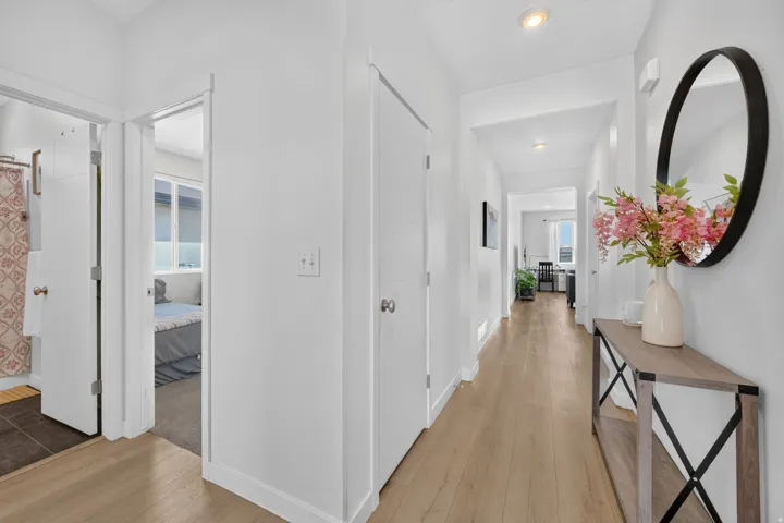 Recessed lighting, wood-finish flooring, white paneled doors, and a round wall mirror