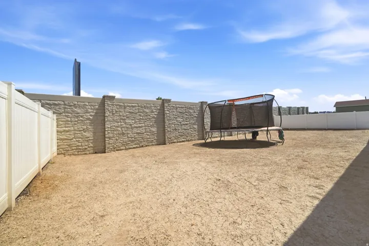Expansive outdoor area featuring a stone-look retaining wall, vinyl fencing, and ample open space