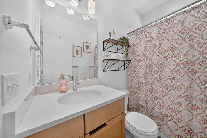 Bathroom featuring a light wood-finish vanity, white countertop with an integrated sink, polished chrome faucet, and a large wall-mounted mirror