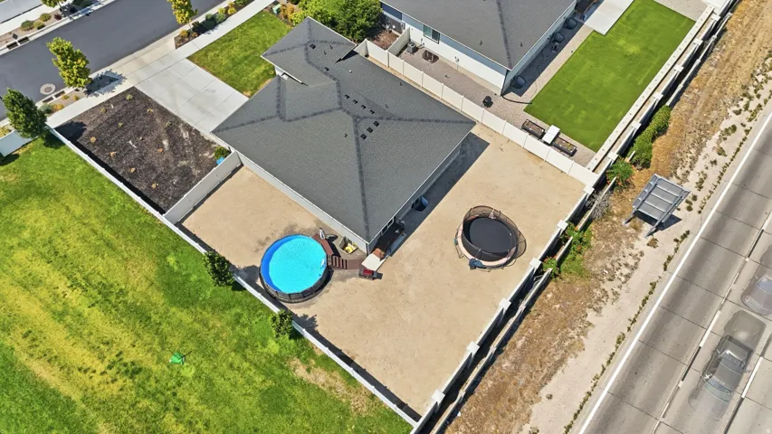Spacious backyard featuring an above-ground pool, gravel hardscaping, and a fully fenced perimeter