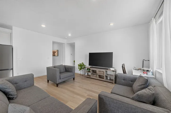 Recessed lighting illuminates the open living area with wood-finish flooring